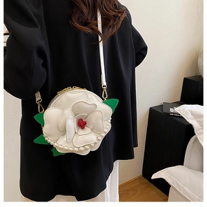 Detail of camellia shaped shoulder bag with pearl trim and green leaf accents