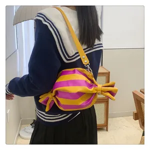 Detail of candy-shaped crossbody bag featuring bold yellow and pink stripes with shoulder strap