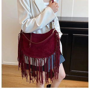 Close-up of bohemian burgundy suede tote bag featuring long fringes and half-moon shape