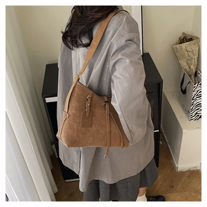 Detail of a brown suede tote bag featuring contrast stitching and adjustable strap