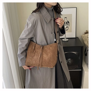 Detail of vintage brown tote bag with drawstring tassel and fashion tag worn by model