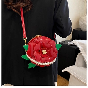 Close-up of red 3D flower crossbody bag with pearl accents and green leaves detail