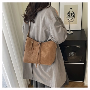 Detailed close-up of a brown vintage tote bag with fringe tassels and a fashion leather tag