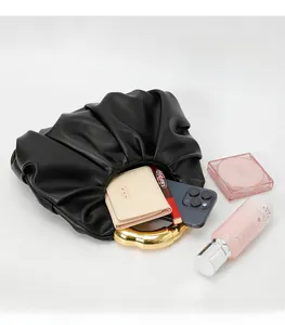 Detail view of black pleated cloud bag with gold ring handle and spacious interior