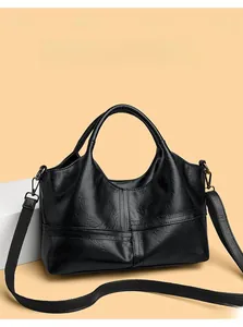 Detail of black textured faux leather handbag with cross stitching and woven strap
