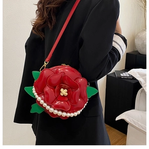 Detail of red flower-shaped leather crossbody bag with pearl chain and green leaf accents