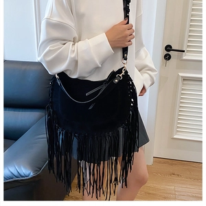 Detail of black suede hobo bag with long fringe tassels and golden metallic hardware