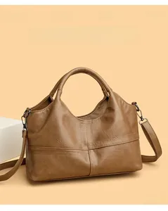 Detail of vintage brown leather handbag with cross stitching and adjustable shoulder strap