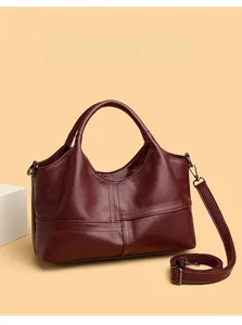 Detail of wine red faux leather handbag featuring stitched cross and fabric strap