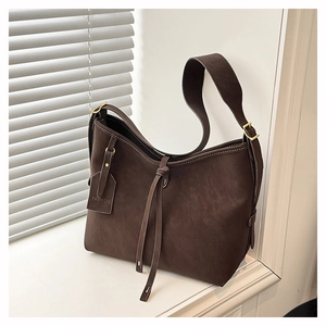 Detail of dark brown tote bag with white contrast stitching and gold hardware buckle