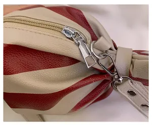 Detail of smooth silver zipper and red-beige striped texture on candy-shaped bag