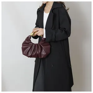 Detail of burgundy ruched dumpling bag with elegant sculptural gold metal handle