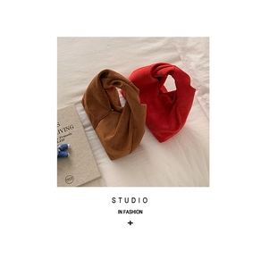 Close-up of caramel brown and red suede mini handbags with twisted knot handles and soft texture