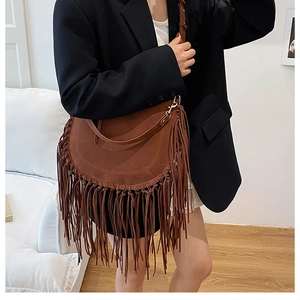 Detail of brown suede hobo bag with long fringes and gold hardware on shoulder strap