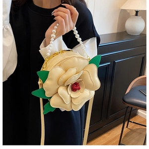 Detail of camellia-shaped round bag with pearl handle and golden hardware accents