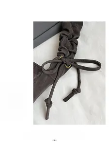 Detail of grey pleated drawstring shoulder strap with vintage bronze metal buckle hardware