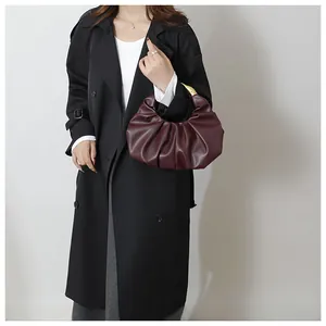 Detail of burgundy ruched cloud bag with sculptural gold metallic top handle