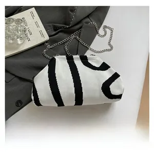 Close-up of zebra pattern knit shell bag on a grey blazer with silver chain strap