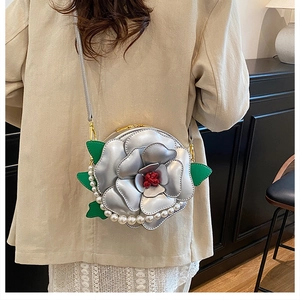 Detail of silver camellia flower crossbody bag with pearl chain and green leaf accents