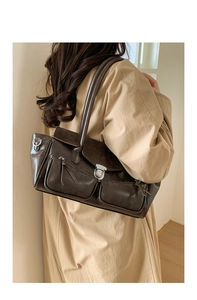 Detail of dark brown retro shoulder bag showing front zipper pockets and metal buckle