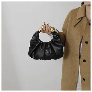 Detail of black ruched cloud handbag with sleek golden metal handle for women