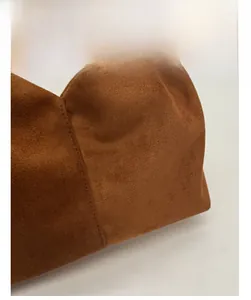 Macro detail of the soft brown suede fabric texture and neat stitching on this handbag