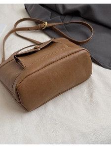 Detail view of brown vintage leather crossbody bucket bag with fine stitching and gold buckle