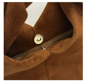 Detailed close-up of the metal magnetic buckle on a caramel suede pleated handbag