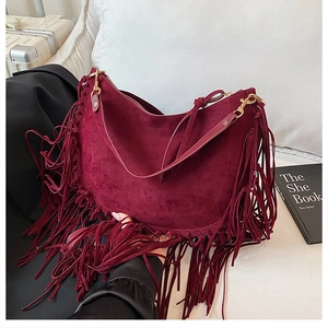 Detail view of a burgundy suede tassel bag with golden hardware in a bohemian retro style