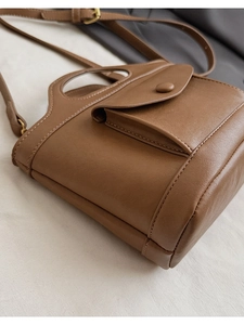 Detail of vintage brown leather bucket bag showing fine stitching and gold hardware buckle