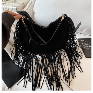 Detail view of black suede half-moon bag with long fringe tassels and gold hardware