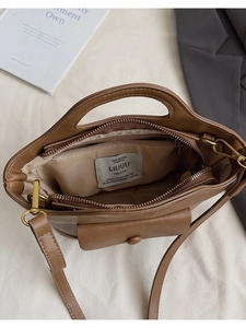 Close-up of brown bucket bag interior featuring a zipper pocket and a front flap pocket