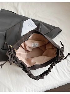 Detail view of large tote bag with pleated handles and inner zip pocket lining