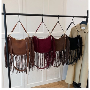 Bohemian suede fringe shoulder bags in four colors hanging on a minimalist display rack