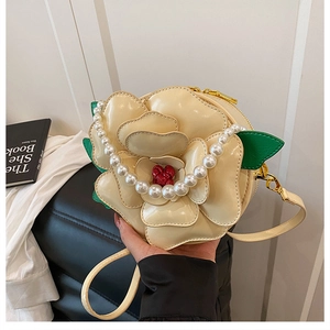 Detail of camellia-shaped shoulder bag featuring pearl handle and golden zipper