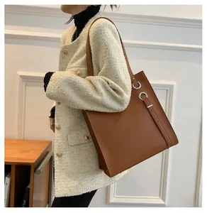 Detail of dark brown leather tote bag with silver metal buckles and adjustable straps