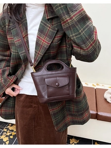 Detail view of a vintage dark brown bucket bag with front pocket and round handle
