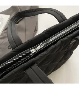 Dettaglio della cerniera argentata e del tessuto trapuntato nero della borsa tote
