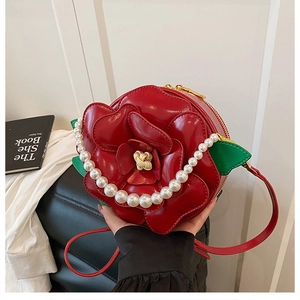 Detailed view of red rose-shaped handbag with textured petals and pearl handle
