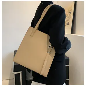 Side view of a beige leather tote bag featuring a silver metal ring and decorative strap