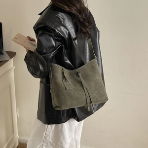 Olive green matte tote bag with drawstring detail shown in a stylish indoor lifestyle scene