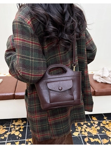 Detail of vintage brown leather bucket bag with front pocket shown in autumn setting