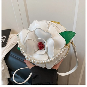 Detail of white camellia floral handbag with pearl handle and gold chain hardware