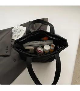 Interno spazioso della borsa tote trapuntata nera con tasca a zip e oggetti quotidiani