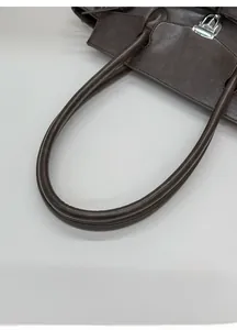 Close-up of minimalist brown tote bag with silver twist lock and pebble grain texture