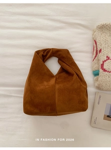 Detail shot of caramel brown suede handbag featuring a unique knotted handle design