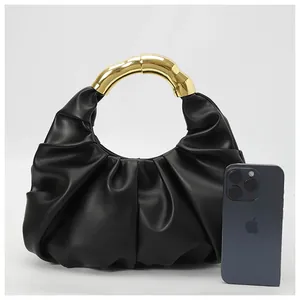 Detail of black pleated cloud bag featuring a golden bamboo-style metal handle