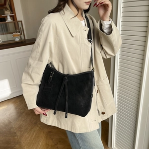 Minimalist black fringe tote bag worn on a beige coat for a stylish daily commute look
