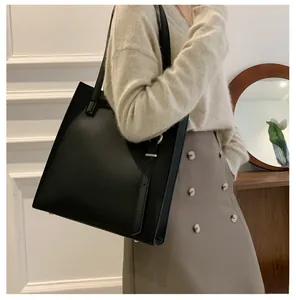 Detail of minimalist black leather tote bag with silver buckle and sleek long shoulder straps