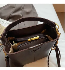 Detail of deep brown bucket bag showing internal zipper compartments and lychee texture